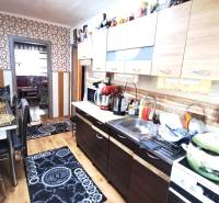 Kuchyně v 2-pokojovém bytě s podlahou s dřevěným dekorem a geometrickými tapetami.