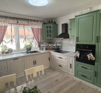 Kuchyně v rodinném domě s dřevěným nábytkem a závěsy.