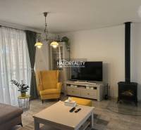 Obývací pokoj v rodinném domě s krbem, žlutým křeslem a televizorem.