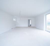 Prostorná světlá místnost v rodinném domě s velkými okny.