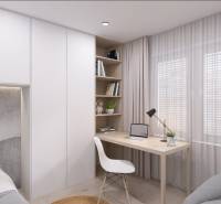 Pracovní kout v rodinném domě s psacím stolem, křeslem a knihami na policích.