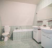 Koupelna s vanou, dvěma umyvadly a zelenými dlaždicemi v hotelech a penzionech.