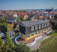 Žlutý hotel s věží, obklopený zahradou ve městě Poprad, hotely a penziony.