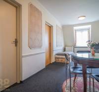 Interiér hotelu a penzionu s kulatým stolem, koberec, TV a ozdobné stěny.