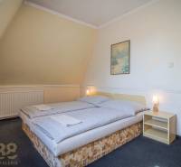 Pokoj s manželskou postelí, noční stolek, obraz, lampa, koberce v hotelu a penzionech.