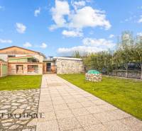 Zahrada u rodinného domu na Kúpeľnej ulici v Dunajskej Stredě s trávníkem a dlažbou.