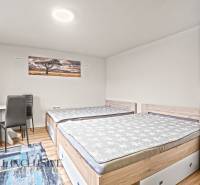 Ložnice v rodinném domě s dvěma postelemi, skříní a podlahou s dřevěným dekorem.