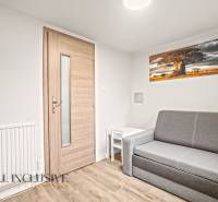 Obývací pokoj v rodinném domě s pohovkou, stolkem a podlahou s dřevěným dekorem.