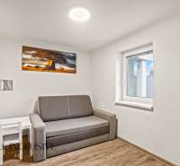 Pokoj rodinného domu s pohovkou, obrazem stromu a podlahou s dřevěným dekorem.