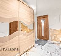 Vstupní hala v rodinném domě s posuvnou skříní a dveřmi v dřevěném dekoru.