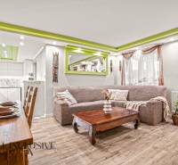 Obývací pokoj v rodinném domě s podlahou s dřevěným dekorem a zelenými detaily na stropě.