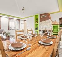 Jídelna v rodinném domě s dřevěným stolem, sklenicemi a dekorativním krbem.