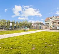 Zahrada rodinného domu na Kúpeľnej ulici v Dunajské Stredě s udržovaným trávníkem a stromy.