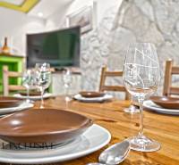 Prostřený jídelní stůl v rodinném domě s podlahou s dřevěným dekorem a kamennou stěnou.