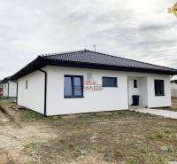 Rodinný dům na ulici v Novém Městě nad Váhom s bílou fasádou a tmavou střechou.