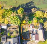 Letecký pohled na pozemek v Jahodné určený k bydlení, obklopený zelení blízko vody.