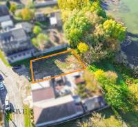 Pozemky - bydlení v Jahodné u řeky, lemované stromy a bohatou zelení.