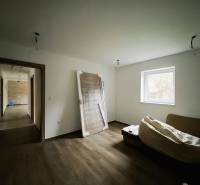 Pokoj v rodinném domě s podlahou s dřevěným dekorem a jednoduchým zařízením.