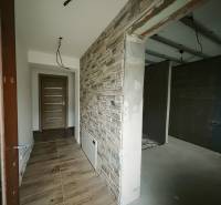 Chodba se stěnou s kamenným dekorem a podlahou s dřevěným dekorem v rodinném domě.