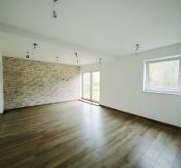 Prostorný obývací pokoj s kameninovou stěnou a podlahou s dřevěným dekorem v rodinném domě.