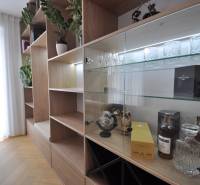 Interiér rodinného domu se skříní, skleněnými policemi a podlahou s dřevěným dekorem.