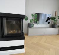 Obývací pokoj v rodinném domě s krbem, televizí a podlahou s dřevěným dekorem.