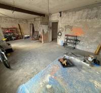 Nedokončená místnost v rodinném domě s kolem a regály pro různé nástroje.