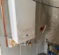 Kotelná rodinného domu ve Staré Kremničce s plynovým kotlem připevněným na stěnu.