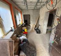 Pokoj v rodinném domě s rekonstrukcí. Stavební materiál, okna zakrytá fólií.