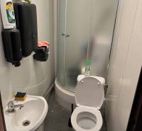 Malá koupelna se sprchovým koutem, umyvadlem a toaletou ve skladech a halách.