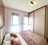 Pokoj se světlým nábytkem a dekoračními polštáři v jednopokojovém bytě.