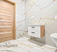 Koupelna v rodinném domě s obkladem a podlahou s mramorovým dekorem.