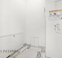 Bílá stěna s poklopem a informačními nálepkami v rodinném domě.