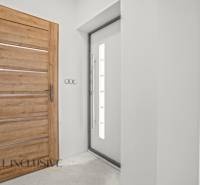 Interiér rodinného domu s dřevěným dekorem a jednoduchými bílými stěnami.