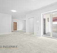 Prostorný interiér rodinného domu s bílými stěnami a velkými okny.