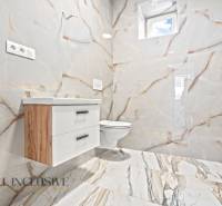 Koupelna v rodinném domě s keramickými obklady a nábytkem s dřevěným dekorem.