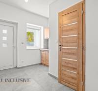 Bílá chodba Rodinného domu s dřevěnými dveřmi a keramickou podlahou.