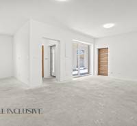 Prostorný interiér rodinného domu s bílými stěnami a dlažbovou podlahou.