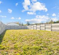 Zahrada rodinného domu v Orechové Potôni s betonovým plotem a travnatým povrchem.