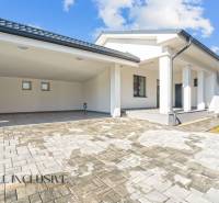 Rodinný dům v Orechové Potôni s terasou a garážovým přístřeškem na dlažbě.