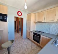 Kuchyně v 3-pokojovém bytě s plynovým sporákem, světlými skříňkami a dlažbou.