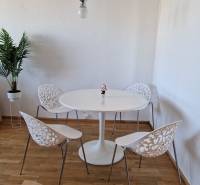 Jídelní kout ve 3-pokojovém bytě s podlahou s dřevěným dekorem a ozdobnými židlemi.