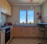 Kuchyně s oknem, podlaha s dřevěným dekorem, dlažba, zařízení ve 3pokojovém bytě.