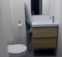 Kompaktní koupelna s umyvadlem a skříňkou v 1pokojovém bytě, obklady s jemnou texturou.