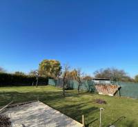 Zahrada u chaty na Nové osadě v Komárně s trávníkem a ohništěm.