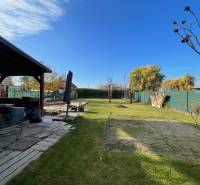 Zahrada u chaty na ulici Nová osada v Komárně, s trávníkem a altánkem.