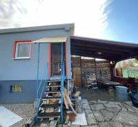 Chata v Komárně na ulici Nové osady s krytou terasou a dřevěným schodištěm.