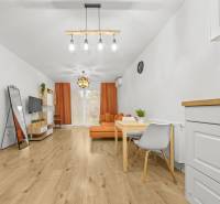 Obývací pokoj v 2-pokojovém bytě s podlahou s dřevěným dekorem a oranžovým nábytkem.