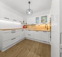 Kuchyně s bílými skříňkami, dřevěnými deskami a podlahou s dřevěným dekorem v 2-pokojovém bytě.