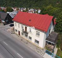 Budova v Belej s červenou střechou, okolní domy a příroda.